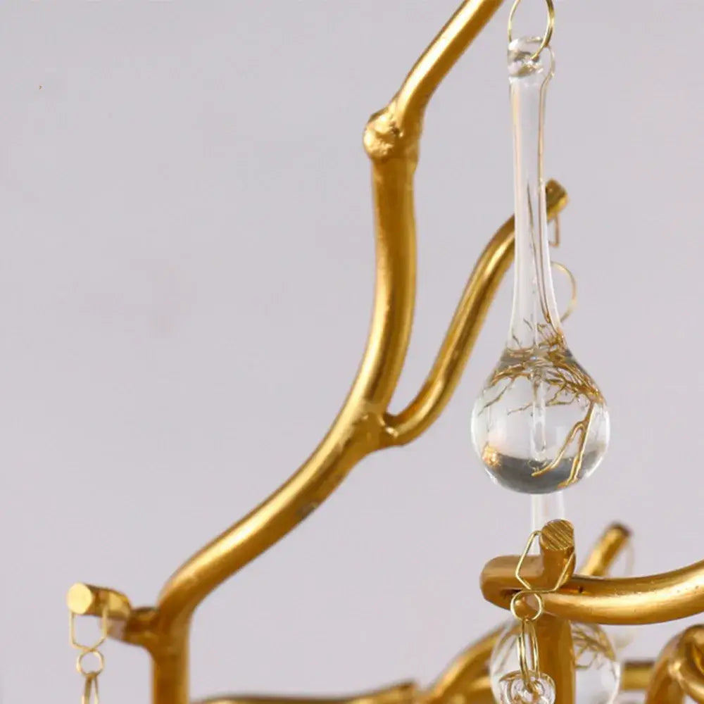 A decorbites™ modern chrome crystal chandelier for living room features a clear teardrop glass pendant with gold wire detailing
