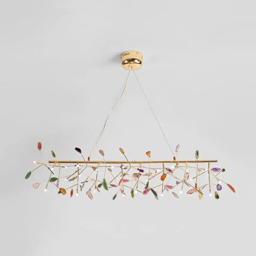 A modern colorful island light fixture with gold metal frame and translucent leaf crystals for warm color temperature