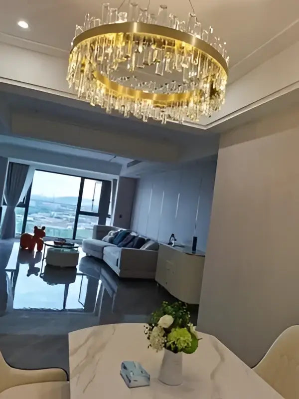 A golden chrome crystal chandelier with dangling droplets designed for modern dining room lighting by DecorBites
