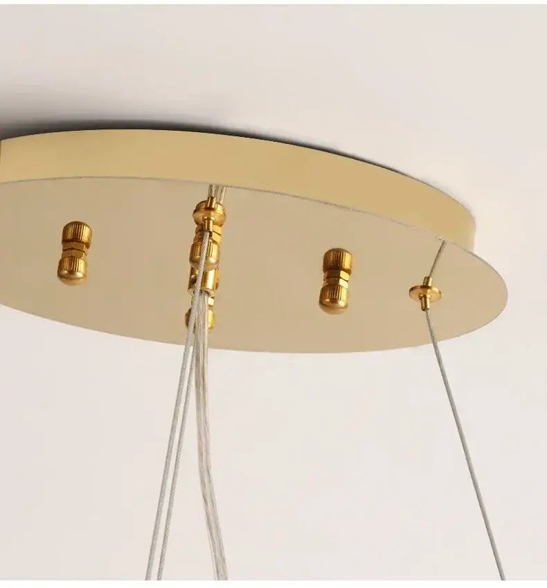 Gold-toned circular ceiling chandelier mount with brass hardware and clear cables for modern crystal living room lighting