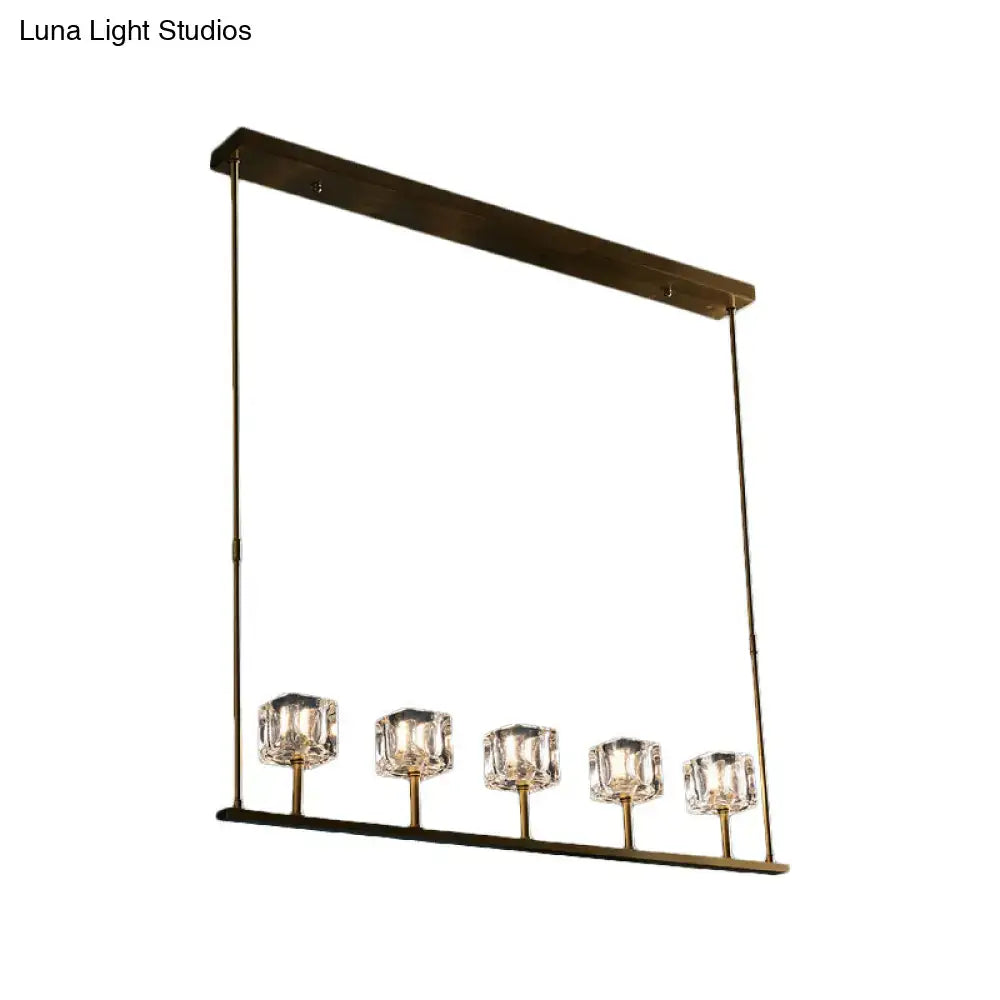 Modern brass-finished rectangular pendant light fixture with five faceted crystal shades for dining area hanging island