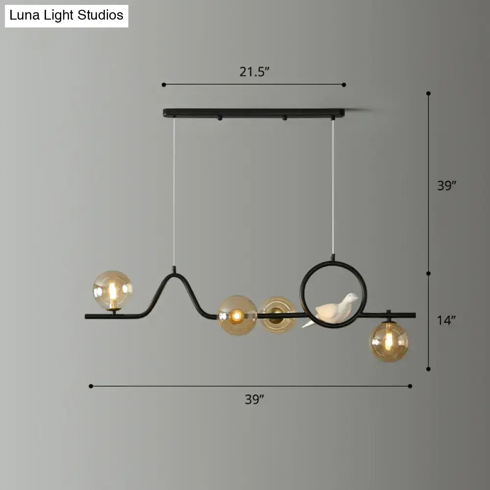 Black metal DecorBites™ curve island ceiling light with five amber glass globes and white ceramic bird for dining room