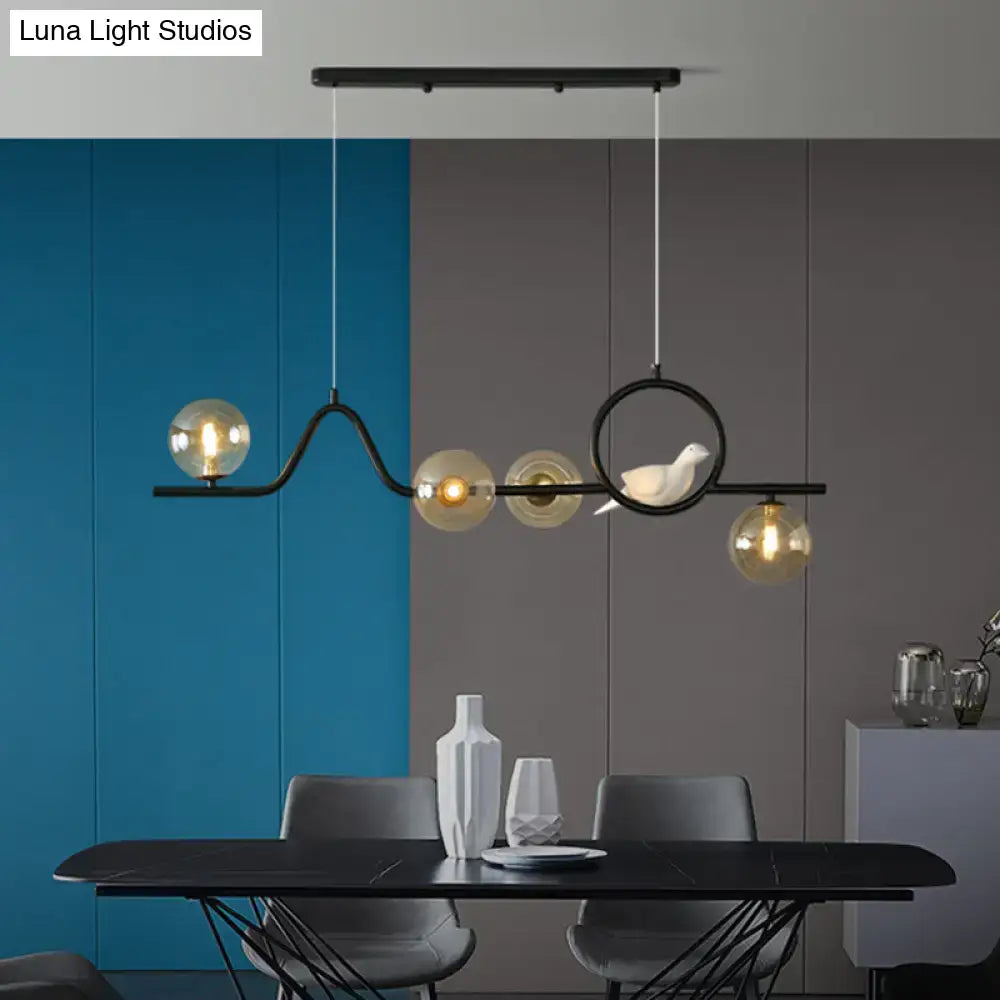 Decorbites™ modern curve island ceiling light with black metal frame, amber glass globes, and white ceramic bird sculpture