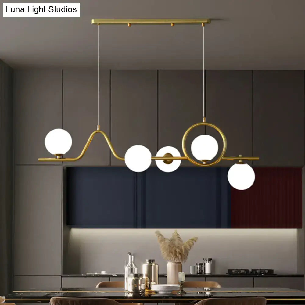 DecorBites™ modern gold-toned curve island ceiling light with five white glass ball shades for dining room