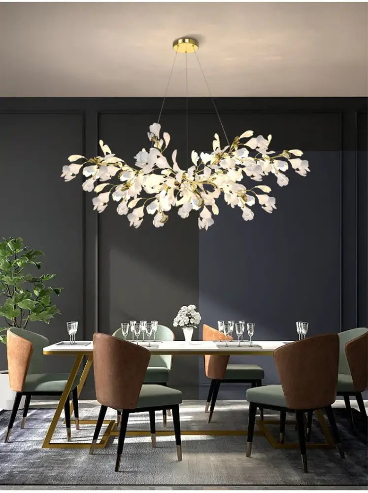 A modern white floral ginkgo led chandelier with gold accents designed for elegant dining room lighting by decorbites