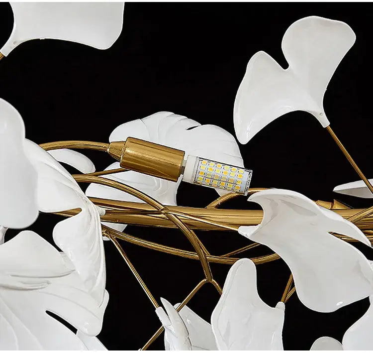 White ceramic ginkgo leaf LED chandelier with gold-toned metal frame for modern dining room lighting by DecorBites™