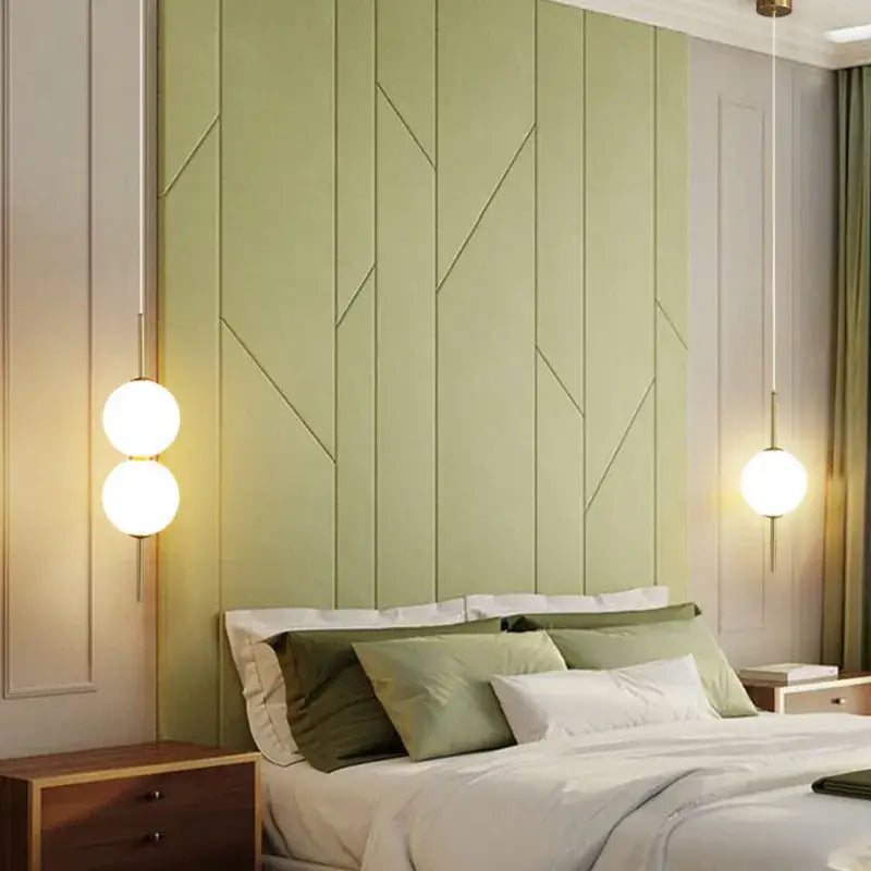 Modern sage green paneled headboard with geometric embossed design next to modern glass pendant lighting fixture