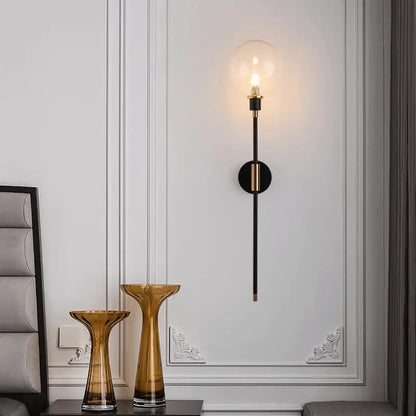 DecorBites™ modern glass wall sconce with black slender stem gold-toned accents and clear glass globe encasing bulb