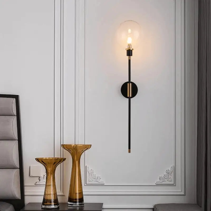 DecorBites™ modern glass wall sconce with black slender stem gold-toned accents and clear glass globe encasing bulb