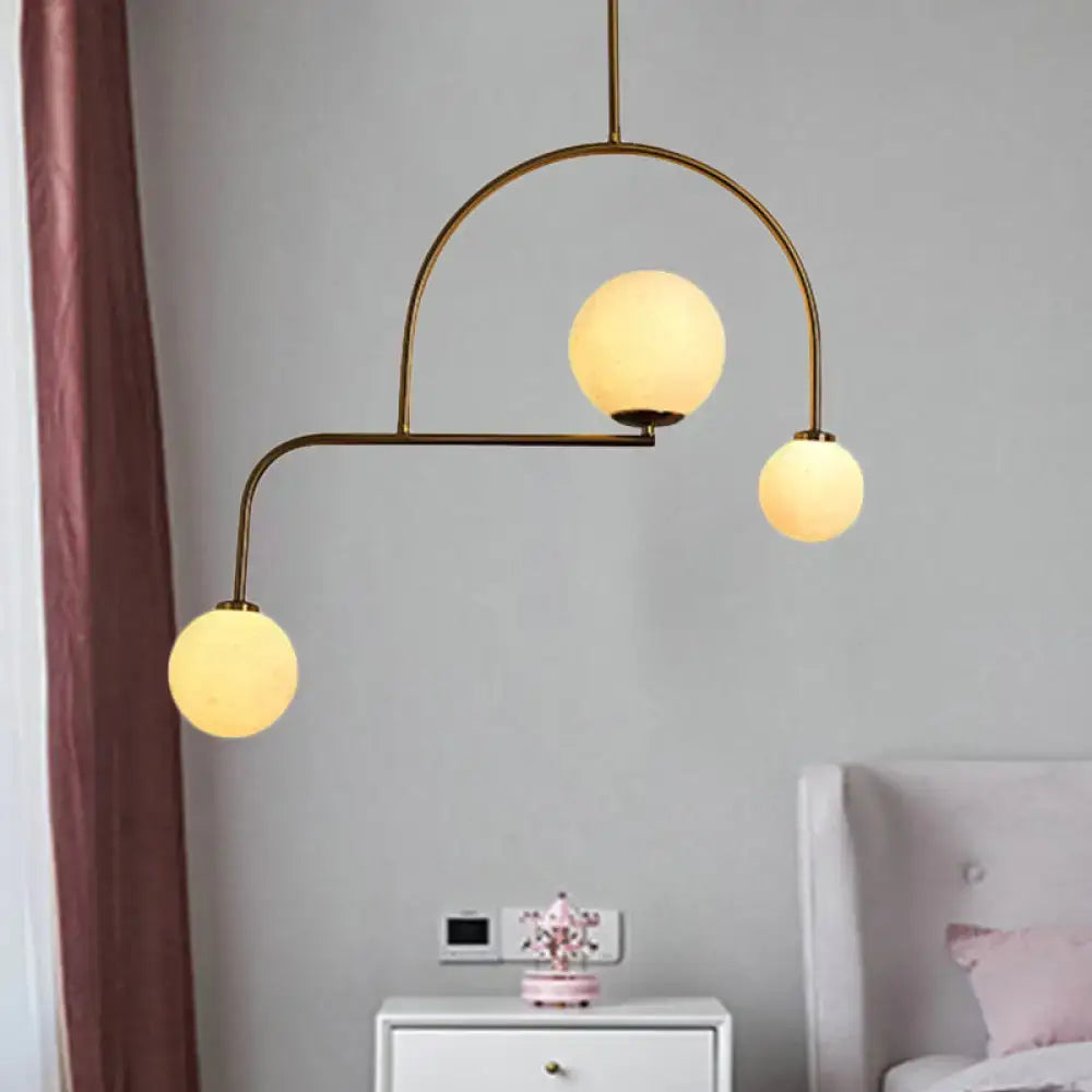 Gold-toned DecorBites Modern Global bedroom chandelier with three yellow white frosted glass globe bulbs in an arched design