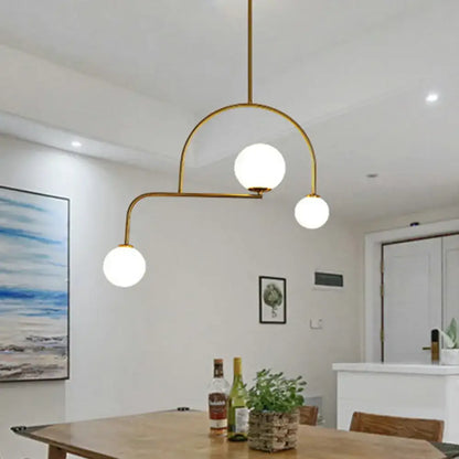 Gold-toned modern global bedroom chandelier with three yellow white frosted glass globes and LED hanging light kit