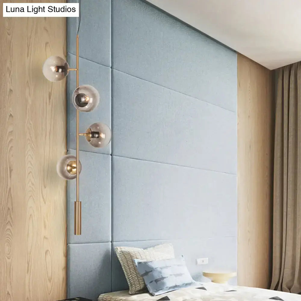 DecorBites modern gold linear chandelier with slender brass stem and four spherical smoke gray glass shades