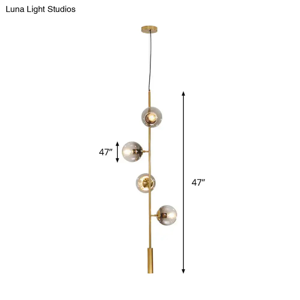 Modern brass pendant light with four vertically arranged gray glass shades on a slender metal rod by DecorBites™