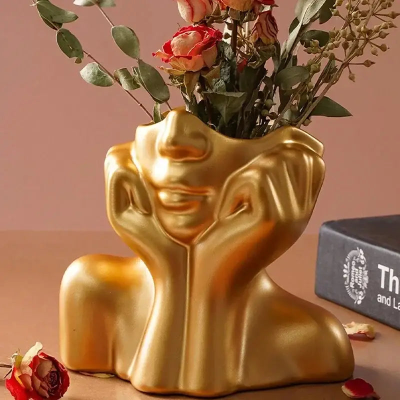 Golden human body shaping resin vase by DecorBites holding dried roses and eucalyptus in a modern design