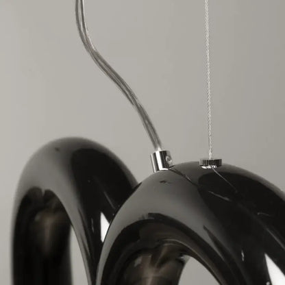 Black glossy resin oblure arch chandelier with sleek curved ring design and metallic suspension hardware by decorbites