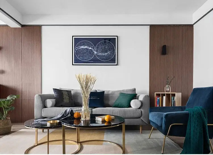 Gray upholstered sofa with dark green and navy pillows beneath a gold black decorbites modern led chandelier for living room