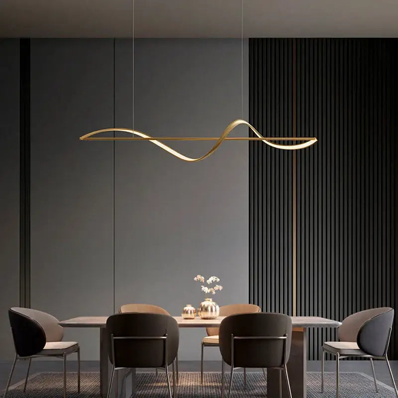 Gold-colored sleekly curved modern led chandeliers pendant lights hanging above a dining table by decorbites