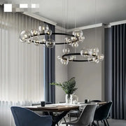 Modern black metal chandelier with adjustable cord featuring clear glass bubble bulbs in concentric circular patterns