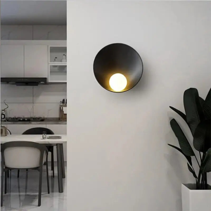 Black matte-finished decorbites modern led wall light with circular bowl-shaped design and warm illuminated bulb