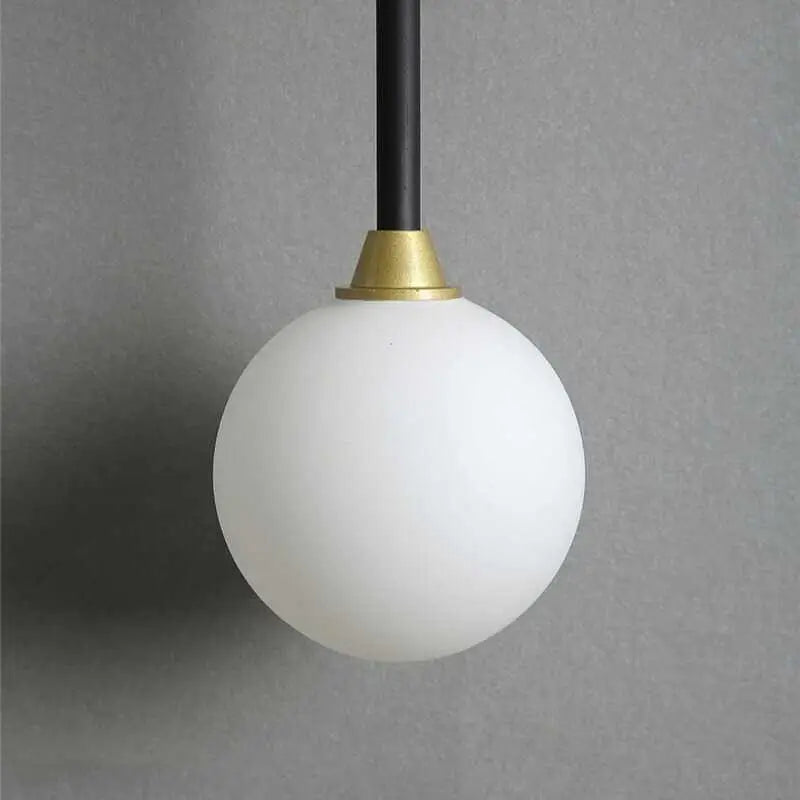 DecorBites™ modern wall sconce with frosted white globe, black rod, and gold accents in a minimalist pendant light design