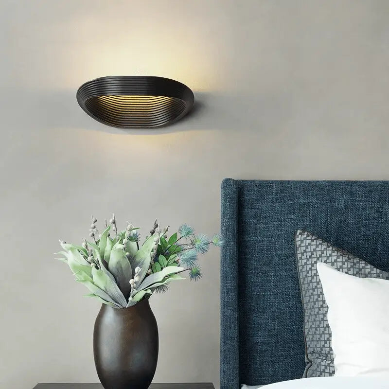 Black oval DecorBites™ modern minimalistic wall sconce with concentric ridged design emitting warm light minimalistic wall sconces