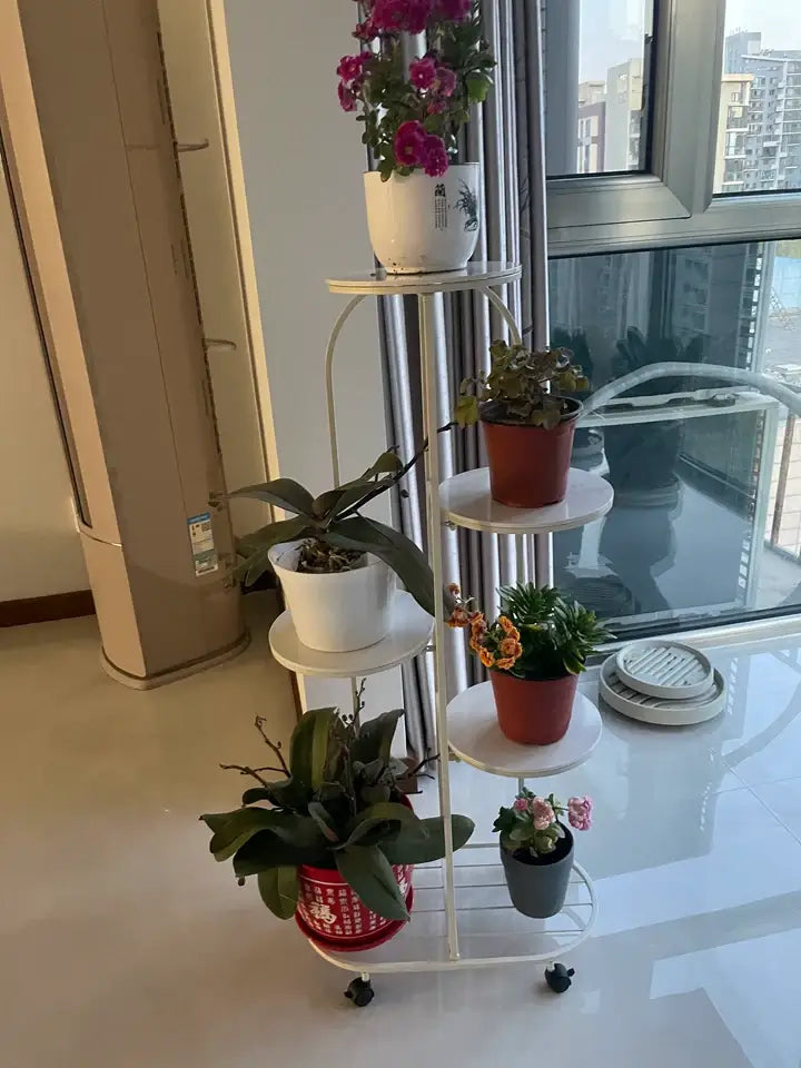 White metal DecorBites™ modern plant stand with four circular shelves and black caster wheels for interior decor