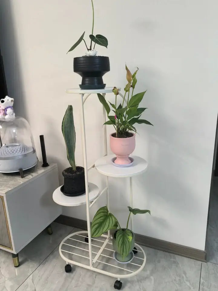 White metal DecorBites™ modern plant stand with four circular shelves and black caster wheels for interior decor
