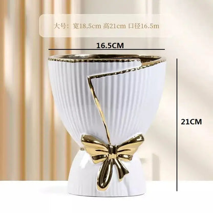 White ceramic vase with gold ribbed texture and decorative gold bow for modern nordic home decor by DecorBites