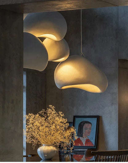 Cream-colored cloud-shaped pendant lights with matte finish hang as a modern nordic chandelier emitting warm light in dining room