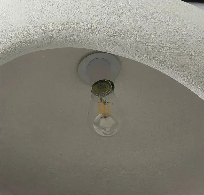 Clear glass led bulb with visible filament in white fixture of decorbites modern nordic chandelier emitting warm light