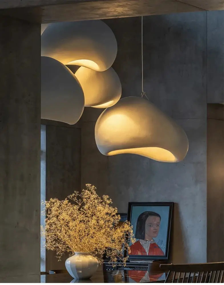 Cream-colored cloud-shaped pendant lights with matte finish hang as a modern nordic chandelier emitting warm light in dining room