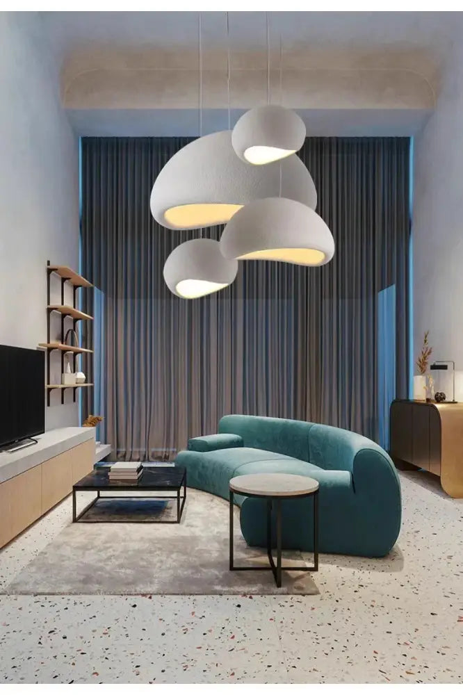 Teal curved velvet sofa with sleek black metal legs complementing modern nordic chandelier with warm light turn