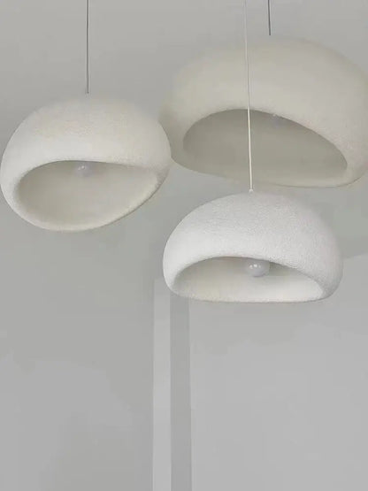 Three minimalist white pendant lights with soft textured domes create warm light in the modern nordic chandelier decorbites