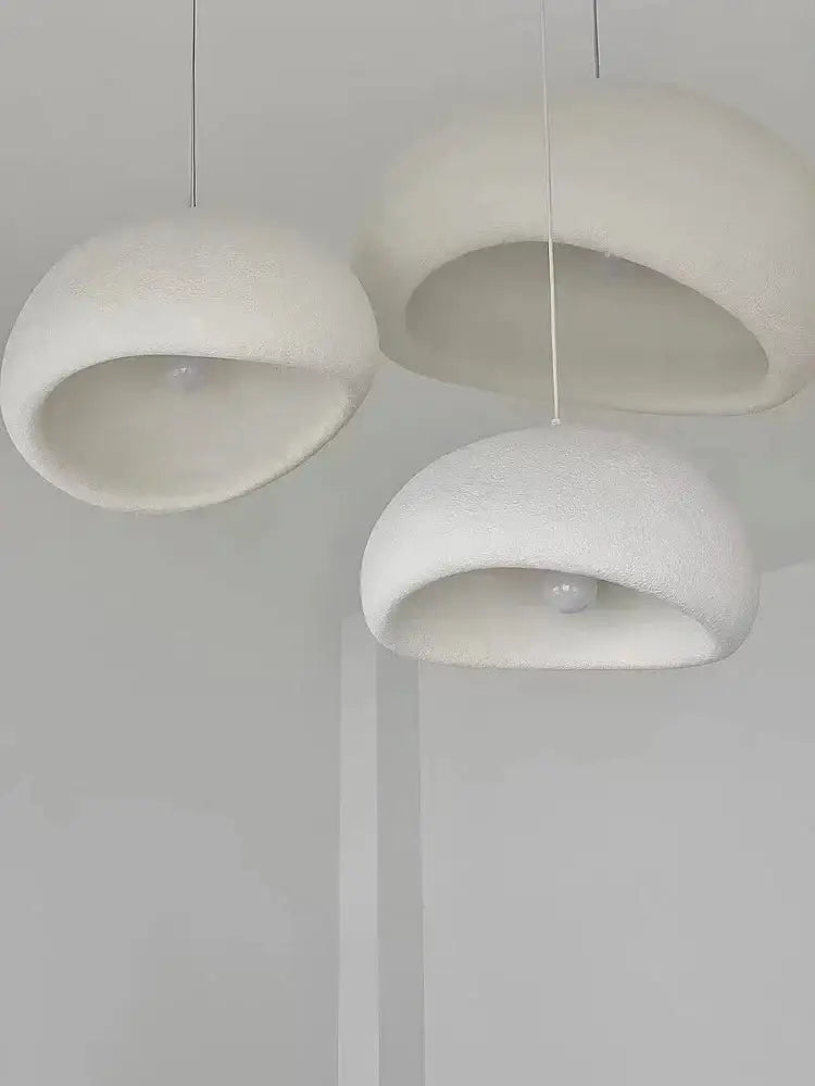 Three minimalist white pendant lights with soft textured domes create warm light in the modern nordic chandelier decorbites