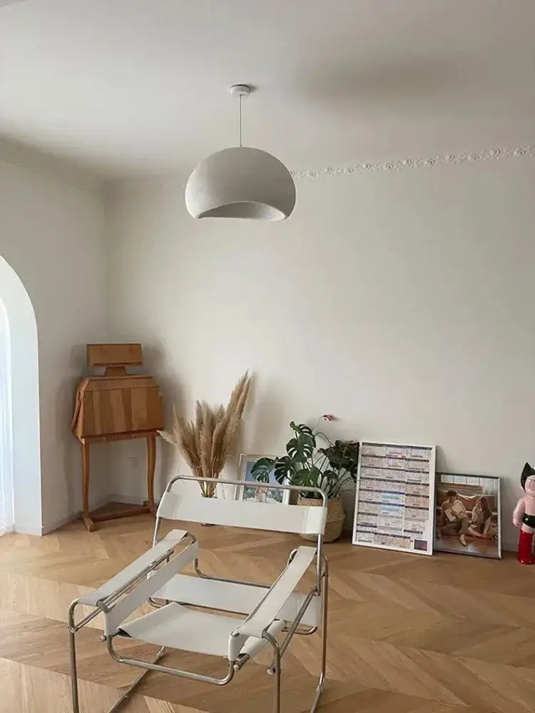 White metal-framed chair with white fabric seat paired with DecorBites™ modern nordic chandelier emitting warm light