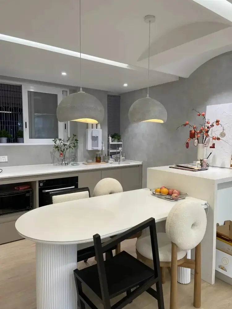White oval dining table with fluted pedestal base illuminated by DecorBites™ modern nordic chandelier warm light