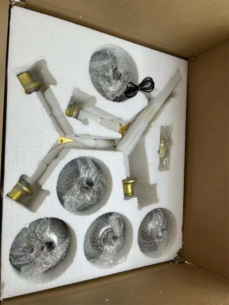 Set of five silver ammonite-shaped decorative objects with gold caps in foam for modern nordic glass chandeliers packaging