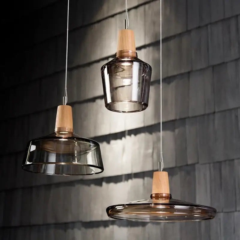 DecorBites modern nordic glass light fixtures with smoked glass shades and light wood accents against dark wall