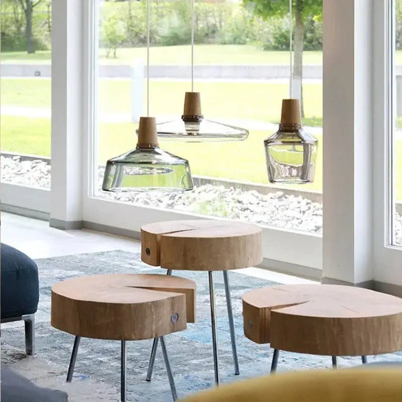 Three rustic wooden side tables with natural wood grain and metal legs complement DecorBites™ glass light fixtures