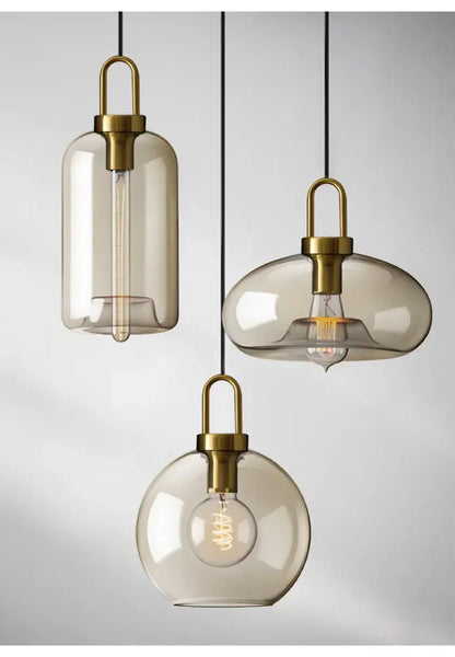Three modern DecorBites™ pendant lights with smoked glass shades brass hardware and visible filament bulbs for kitchen use