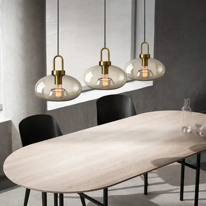 Three modern brass-finished decorbites glass pendant lights with smoke-gray shades for kitchen and restaurant use