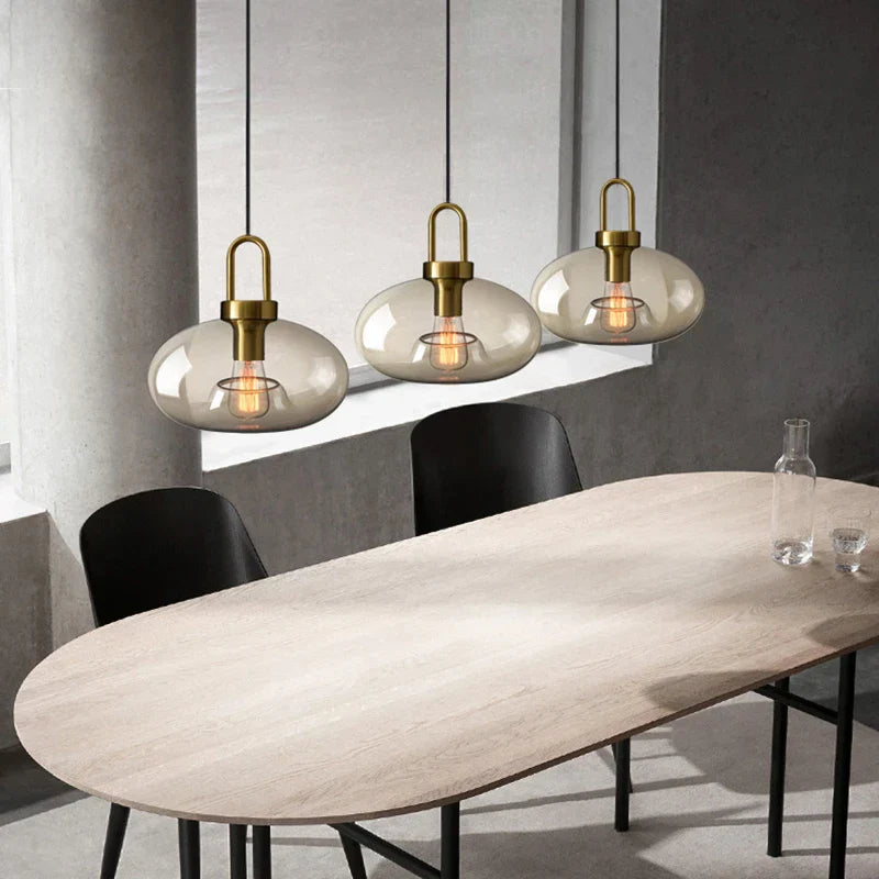 Three modern brass-finished decorbites glass pendant lights with smoke-gray shades for kitchen and restaurant use