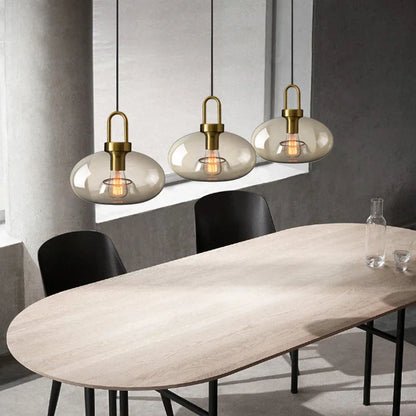 Three modern brass-finished decorbites glass pendant lights with smoke-gray shades for kitchen and restaurant use