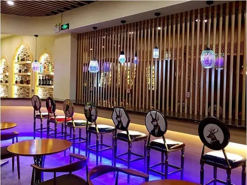 Black chairs with white deer head designs and dark wooden frames complement modern nordic glass pendant lighting