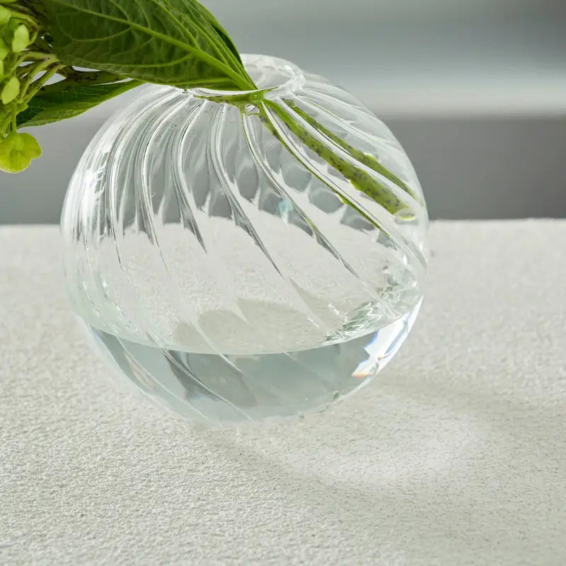 Decorbites modern nordic clear glass spherical vase with swirling ribbed texture holding green hydrangea stems