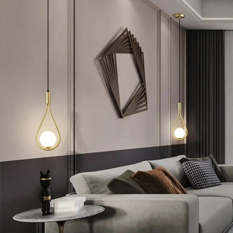 Gold teardrop pendant light with sleek modern nordic pendant design hanging from the ceiling by DecorBites