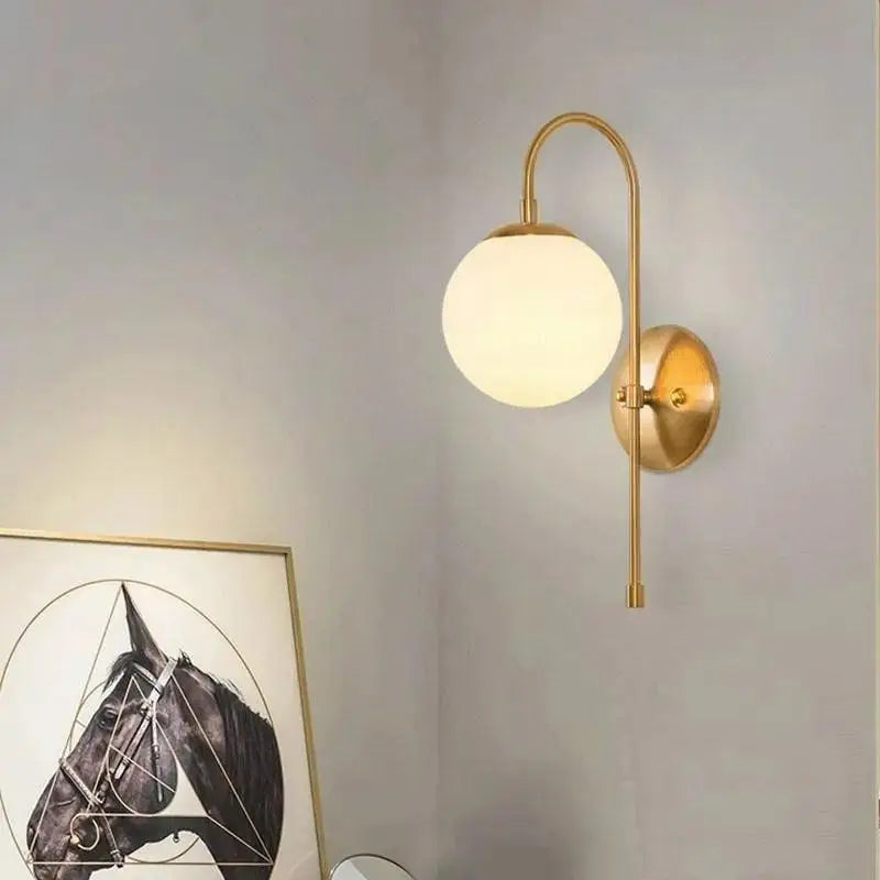 Gold-toned olsson wall lamp with curved arm and frosted glass globe shade in decorbites modern nordic design