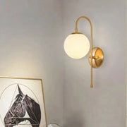 Gold-toned olsson wall lamp with curved arm and frosted glass globe shade in decorbites modern nordic design