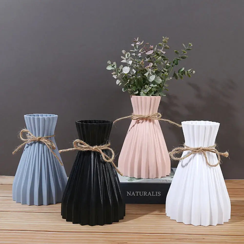 A set of four modern simple pleated ceramic flower vases in pastel and matte black tied with rustic twine for dry flowers