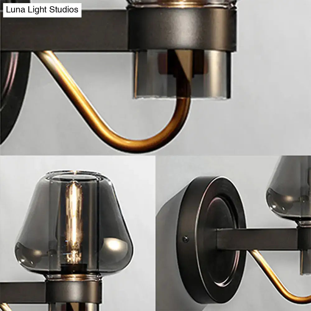 Industrial-style wall sconce lighting fixture with modern smoked glass mushroom shades in black metal and brass accents